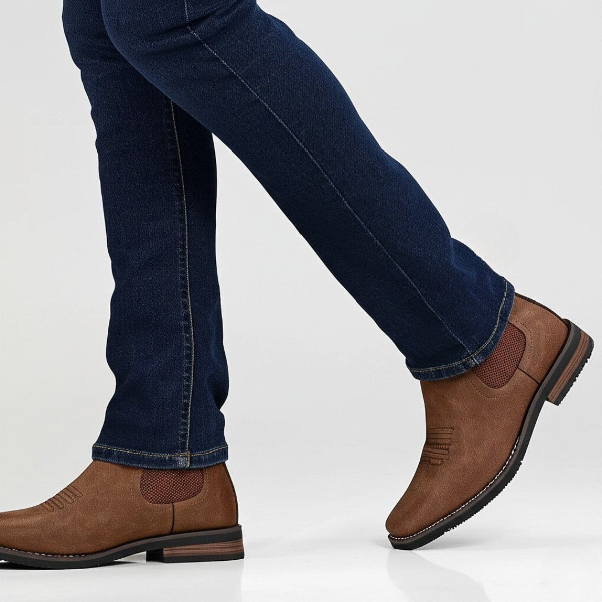 Man wearing brown wide toe box Chelsea boots with dark denim jeans, side view