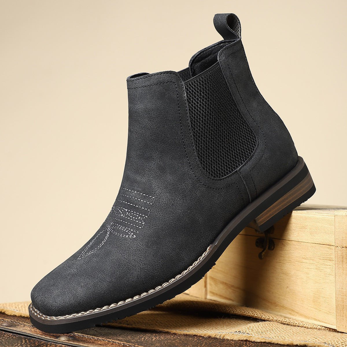 Dark gray wide toe box Chelsea boot for men propped on a wooden crate, showing the elastic side panel