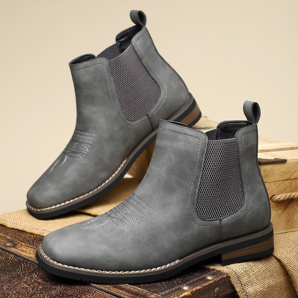 Gray wide fit Chelsea boots for men with stacked heel and rear pull tabs, shown as a pair on wooden crates