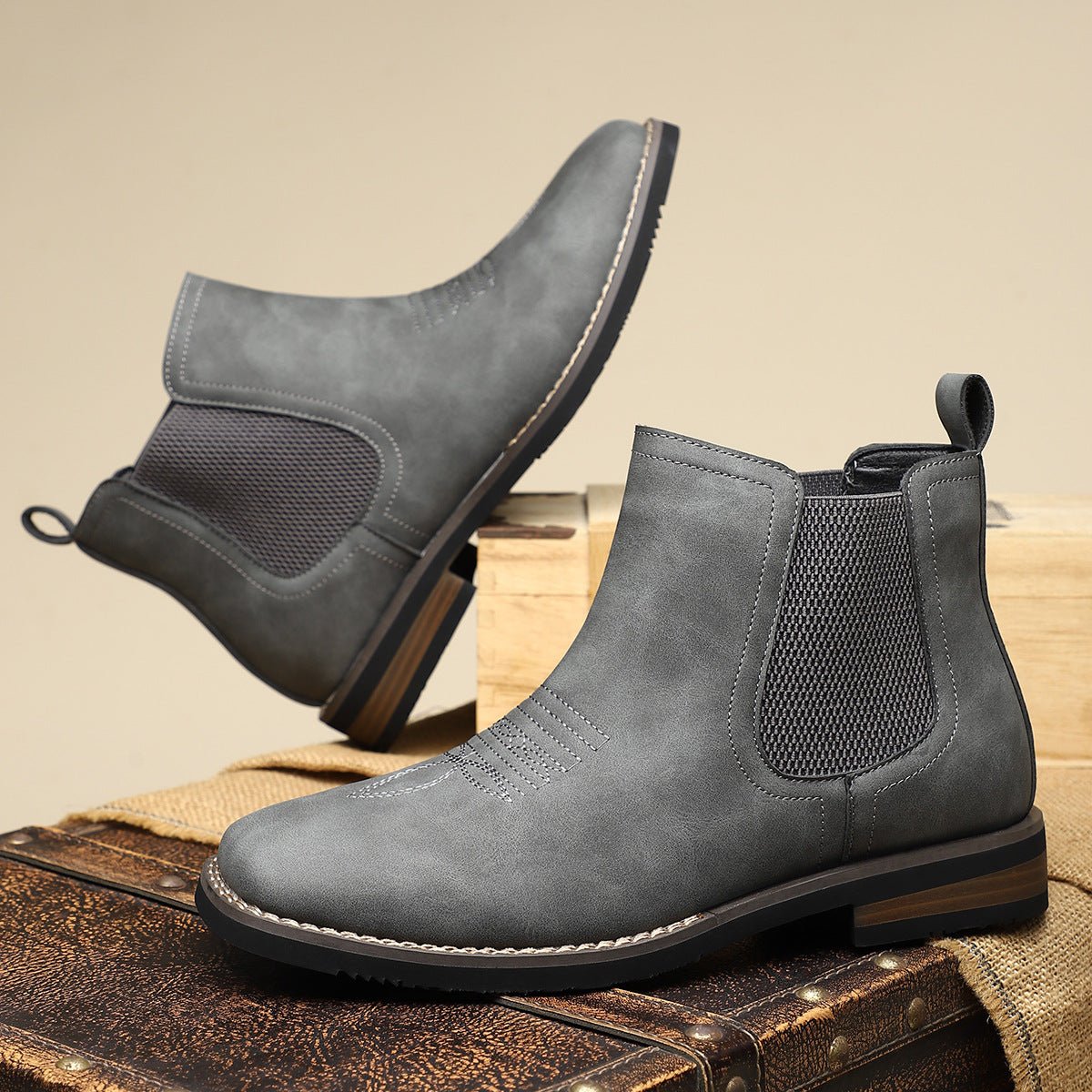 Gray wide toe box Chelsea boots for men, one tilted to show the stitched sole edge and low stacked heel