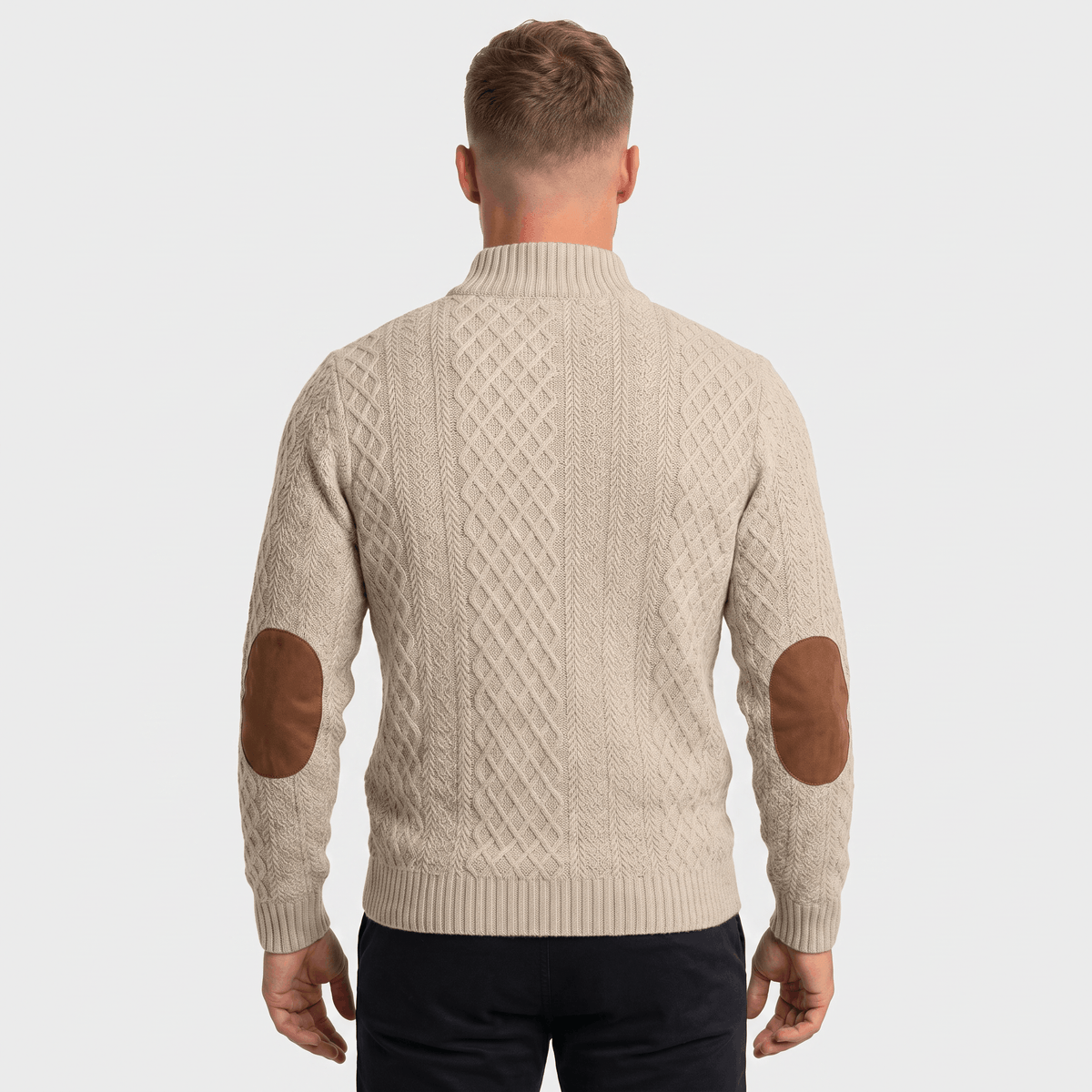 Man wearing a gray cable knit Henley sweater with a stand collar, button placket, faux suede elbow patches, and a modern fit.