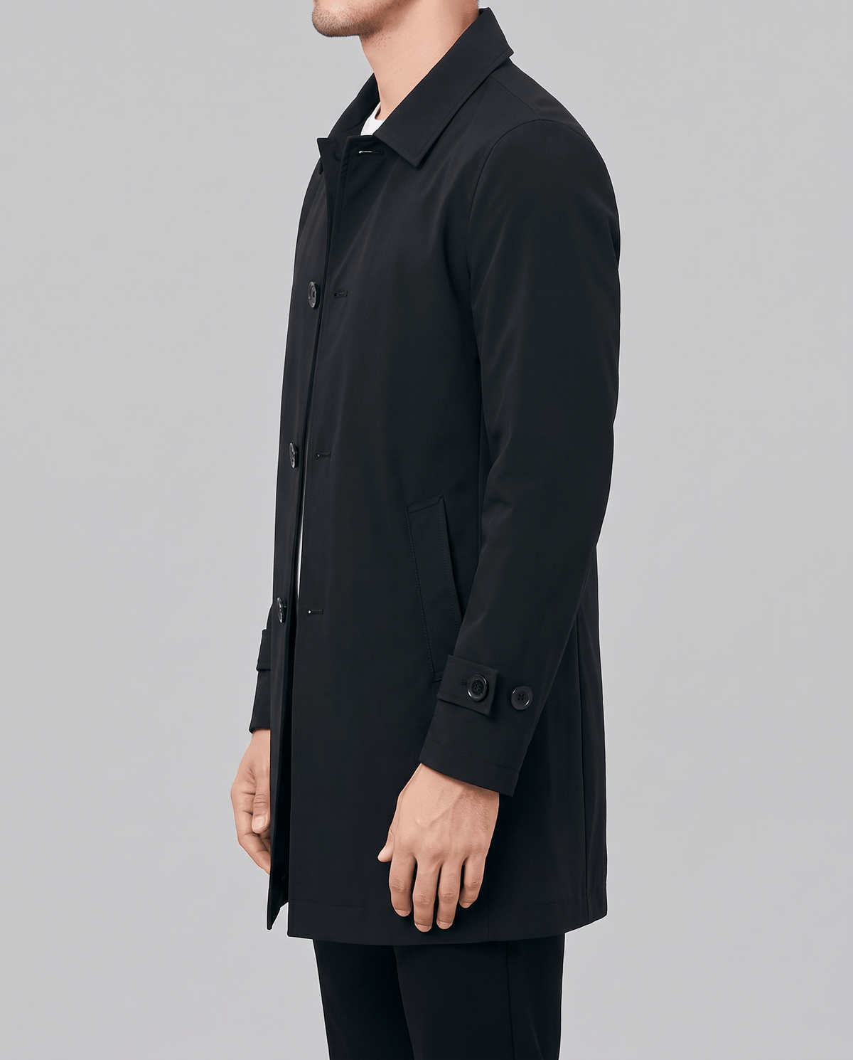 A man wearing a black wool blend mid-length trench coat with a tailored fit and weatherproof finish, shown in side view